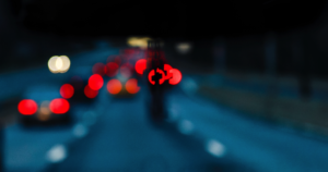 An image of taillights on a twilight freeway, with the outline of a cross in the middle of the center.