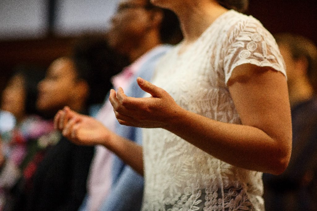 Image: A woman extends her hands in prayer